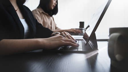 Cropped shot of online on tablet computer while sitting at modern workplace.の写真素材