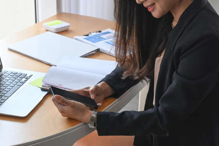 Smiling businesswoman holding plastic cup of fresh juice while standing in office.