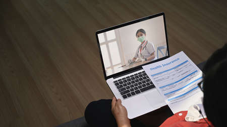 Mature woman patients using computer laptop for online consultation with doctor via video call at...