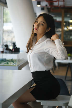 Portrait of attractive young woman office worker relaxing and stretching her body at office.