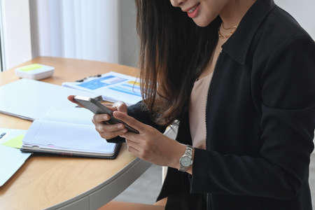 Side view of smiling young woman accountant working on laptop computer at office desk.の写真素材