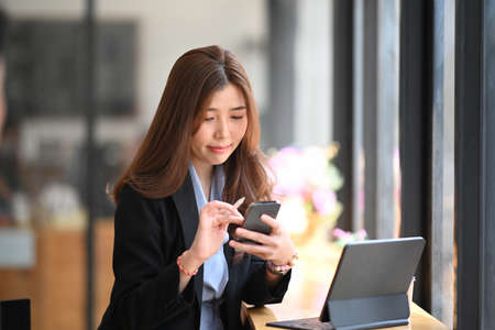 Successful businesswoman working with digital tablet while standing in modern office.の写真素材