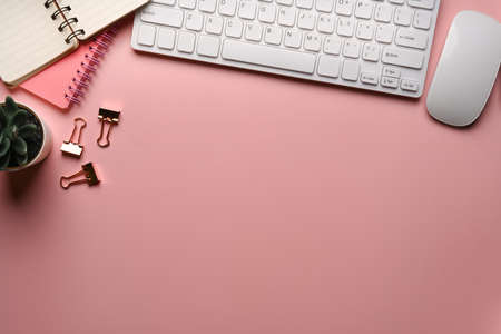Above view of young woman working on laptop computer and holding smart phone at her office desk.の写真素材