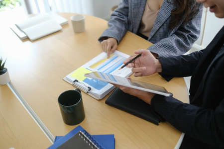 Two young business people using digital tablet and discussing about business strategy.の写真素材