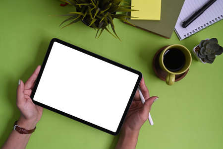 Top view of man holding mock up smart phone with blank screen on white office desk.