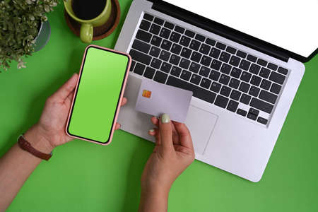 Top view of stylish workplace with keyboard, coffee cup, notebook and copy space on green...