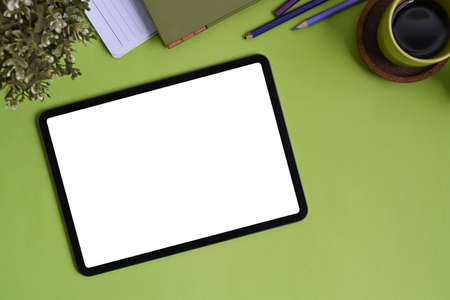 Top view of stylish workplace with keyboard, coffee cup, notebook and copy space on green...