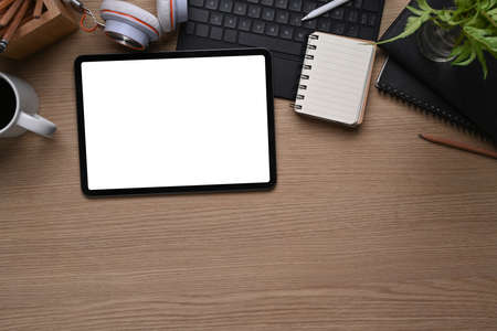 Top view of mock up digital tablet with whit screen, notebook, keyboard, headphone and copy space on...