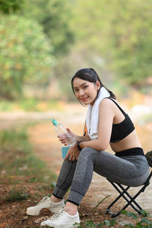 Sporty woman with white towel  setting up her smart watch before workout at the park.