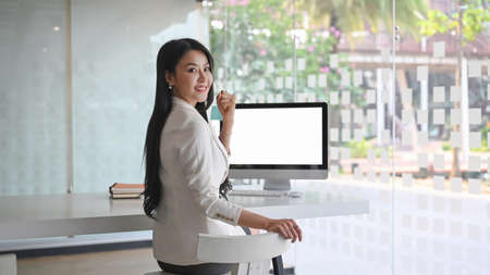 Confident businesswoman showing smart phone with blank screen and smiling to camera.の写真素材