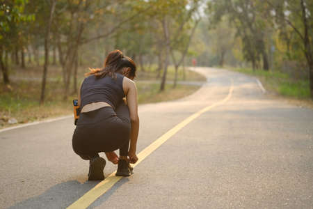 Rear view of fitness woman in  sportswear stretching and exercising in the park.の写真素材
