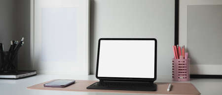 Computer tablet with blank screen, smart phone and stationery on female workplace.