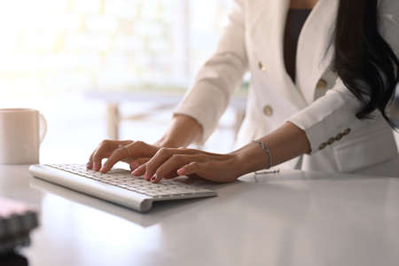 Portrait of businesswoman checking mobile phone and working with computer tablet in office.の写真素材
