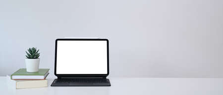 Minimal workplace with computer tablet, books, plant and copy space on white table.の写真素材