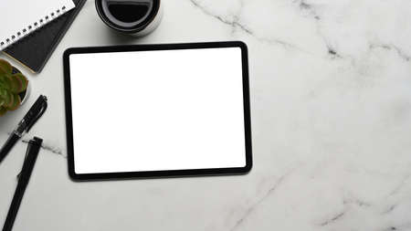 Top view of modern workplace with digital tablet, keyboard, plant and notebook on white office desk.の写真素材