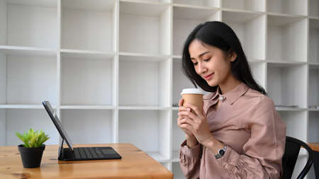 Two businesswoman colleagues using digital tablet searching for business data online in office.の写真素材