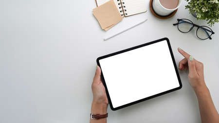Mock up digital tablet, coffee cup, notebook and cactus on white office desk. Blank screen for products display montage.の写真素材