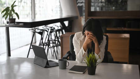 Frustrated businesswoman holding her head feeling upset about problem.の写真素材