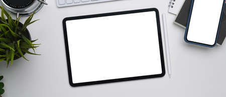 Above view of young woman holding and typing on smart phone at white office desk.