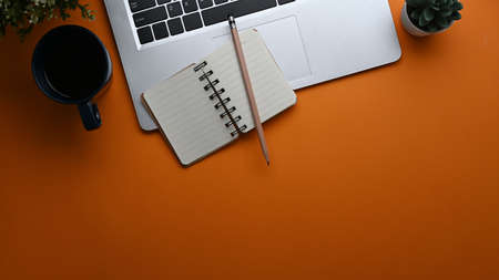 Top view of mock up smart phone , laptop computer, notebook and coffee cup on white office desk.