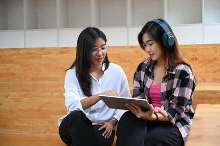 Two young woman creative designer discussing and sharing ideas for startup project in office.の写真素材