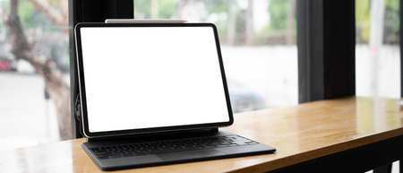 Close up view of computer tablet with blank screen on wooden table near window.