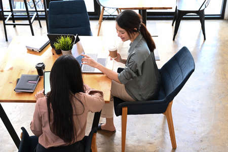 Hight angle view of two business colleagues using digital tablet an analyzing business data on document at office.の写真素材