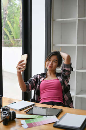 Portrait of thoughtful young woman sitting in coffee shop with her computer tablet and looking out of window.の写真素材
