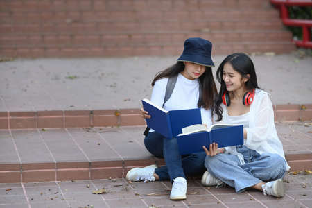 Two asian college student standing in college campus and making research on tablet computer doing homework.の写真素材