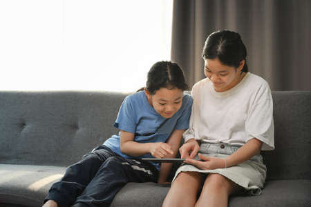 Two happy girls playing game together in comfortable home.の写真素材