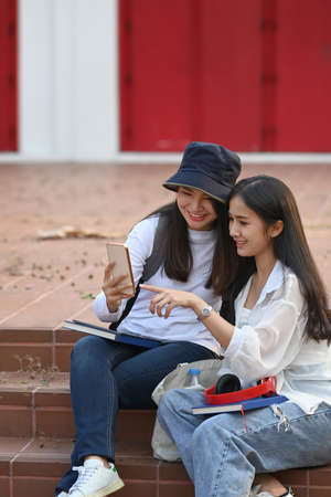 Two asian college student standing in college campus and making research on tablet computer doing homework.の写真素材