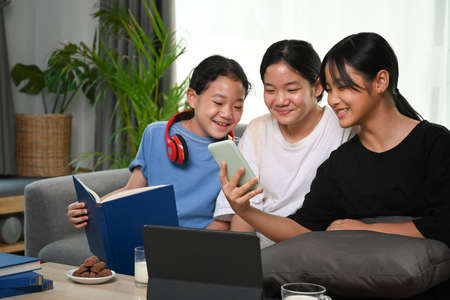 Three asian girl sitting on sofa and using digital tablet.の写真素材