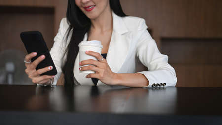 Young businesswoman listening music over earphones and reading a book in the office.の写真素材