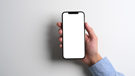 Chiang Mai, Thailand - Apr 2, 2021: Close up view of hand holding smartphone iPhone 12 Pro Max with white screen. Isolated on white background.のeditorial素材