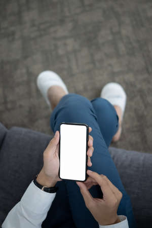 Above view of female sitting on sofa with legs crossed and using mobile phone.の写真素材