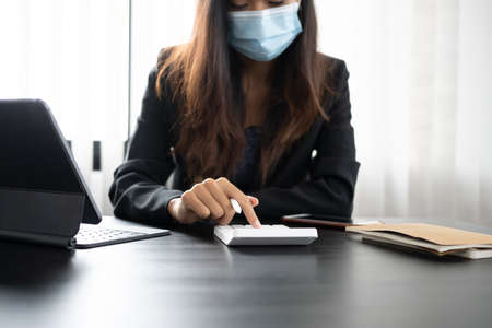 Businesswoman in protective mask concentrate working on computer tablet at office desk.の写真素材