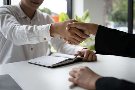 Close up view of businesspeople shaking hands during meeting in modern office.の写真素材