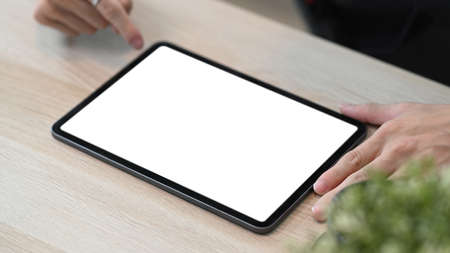 Hight view of businessman holding mobile pone with blank screen on white office desk.
