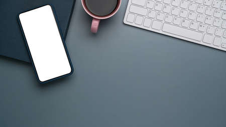 Hight view of businessman holding mobile pone with blank screen on white office desk.の写真素材