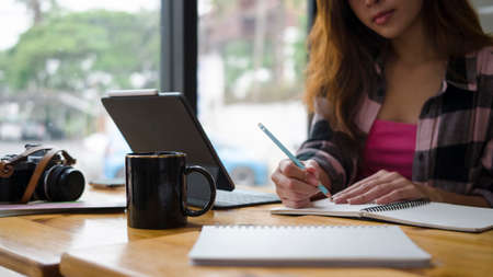 Cropped shot of confident young woman graphic designer working with computer tablet and making note...