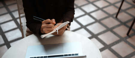 Above view of white office desk with computer laptop, coffee cup, pen and glasses.