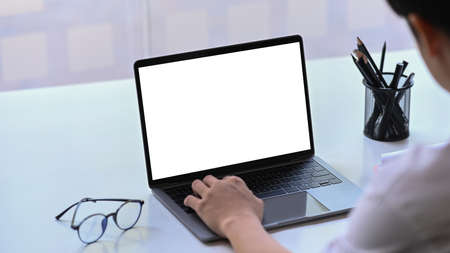 Casual man spending leisure time at home and using computer laptop on sofa .