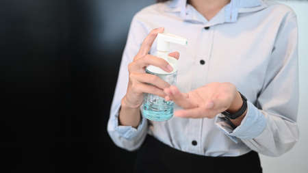 Cropped shot of young female office worker using alcohol hand sanitizer. Hygiene and health concept.の写真素材