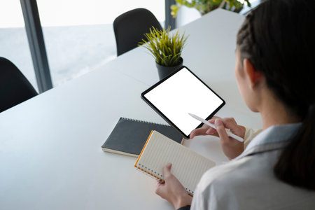 Side view of casual businesswoman sitting in office and using digital tablet.の写真素材