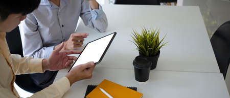 Two young business people using digital tablet and meeting for new project planning in office room.