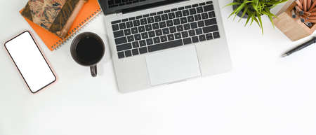 White office desk with digital tablet, notebook, bread and coffee cup.