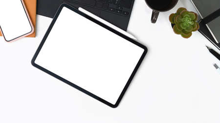 Stylish workspace with smart phone, laptop, notebook, glasses and flowers on orange background.