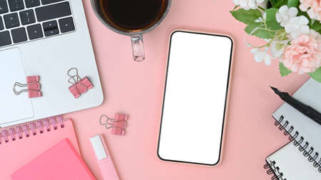 Stylish workspace with smart phone, laptop, notebook, glasses and flowers on orange background.の写真素材