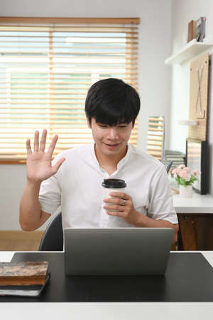Casual man using laptop computer while sitting with his guitar on sofa at home.の写真素材