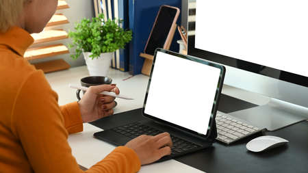 Cropped shot of stylish woman working with digital tablet while siting in modern office.